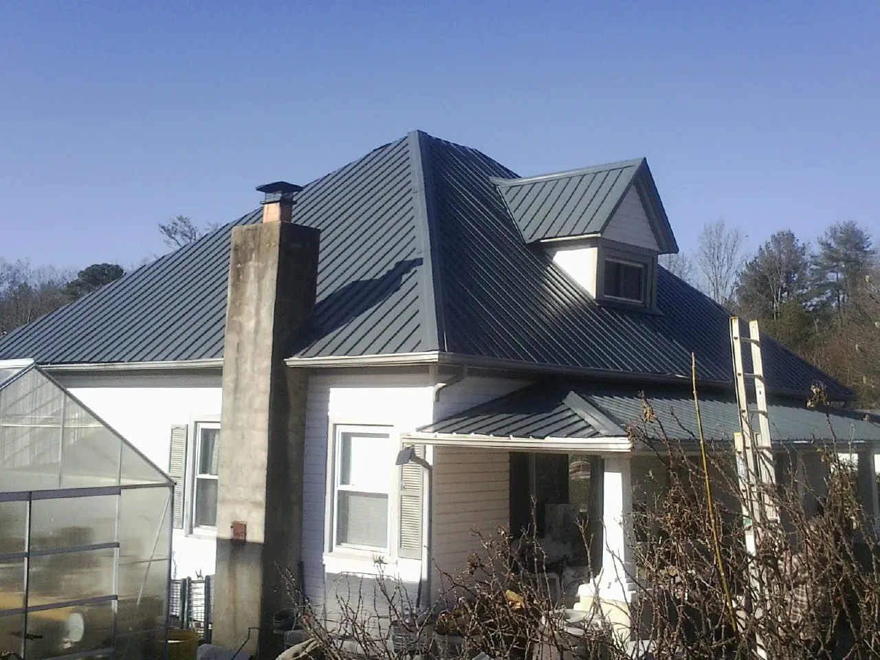 Dark blue standing seam metal roof on a white farmhouse with dormer — Slate & Tile Roof Repair by Roofing Brothers in Myrtle Point