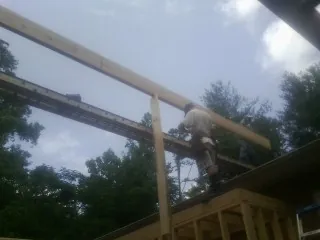 Carpenter setting a ridge beam over a new addition frame — Ice Dam Removal by Roofing Brothers in Myrtle Point