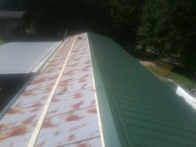 Old rusted panels beside newly installed green metal roofing — Wind Damage Roof Repair by Roofing Brothers in Myrtle Point
