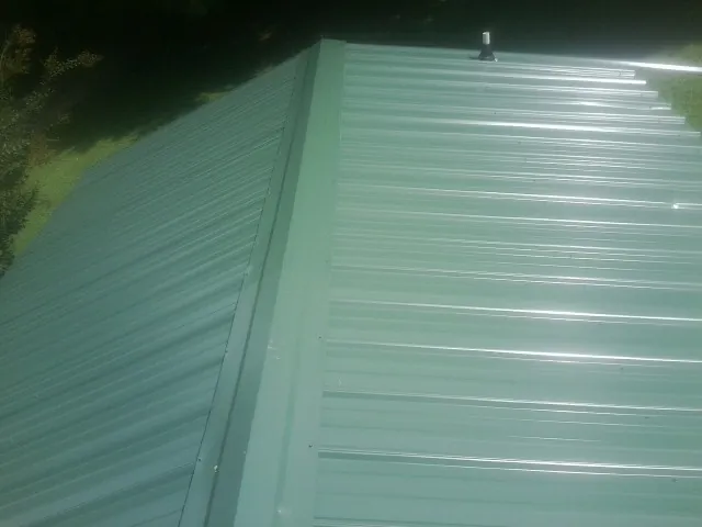 New green metal panels meeting at the ridge of a roof — Flat Roof Repair work by our crew in Myrtle Point