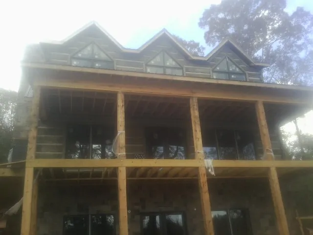 Dormers and porch framing on a large log home under construction — Roof Coating work by our crew in Myrtle Point