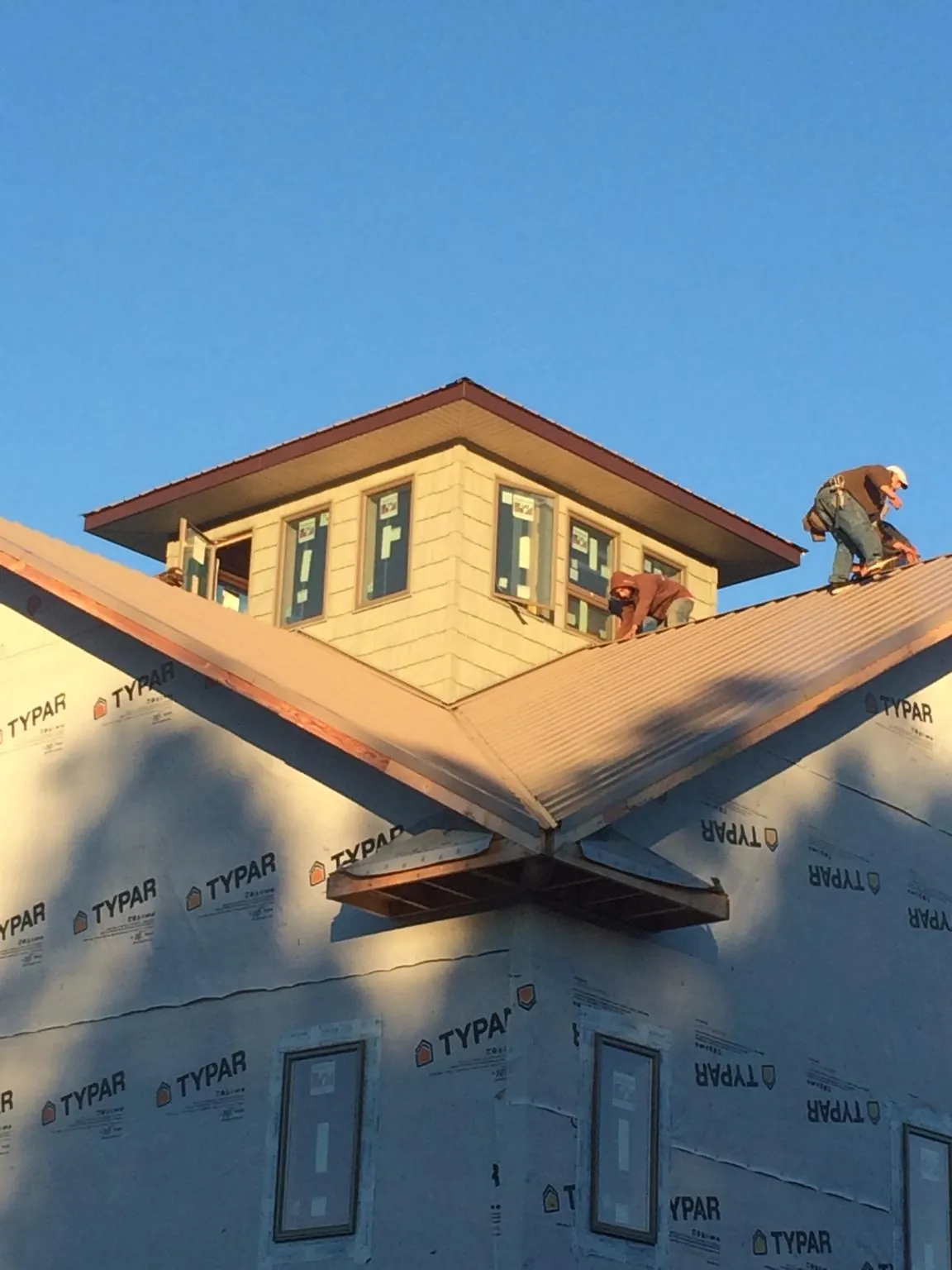Roofers working around a rooftop cupola on a new metal roof at sunset — Roof Waterproofing in Myrtle Point by Roofing Brothers